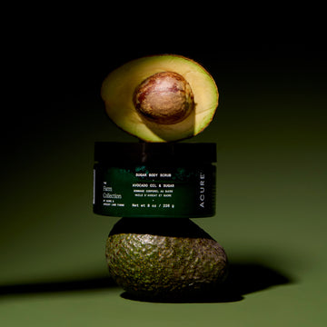 Avocado body scrub jar with half an avocado on a dark green background